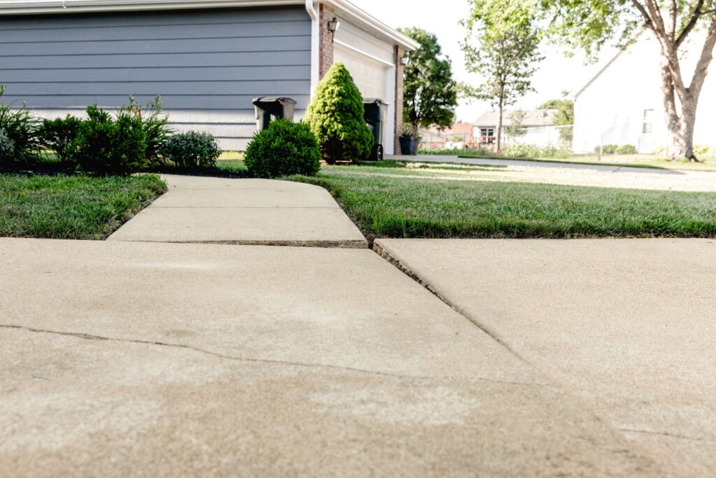 Concrete Repair for Cracked and Settled Sidewalk a sidewalk and grass in front of a house